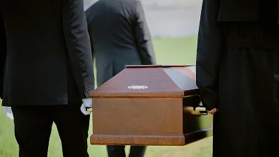 People wearing black suits and white gloves carrying a polished wooden casket.